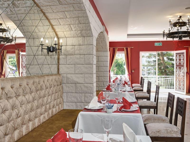 Restaurant élégant avec murs rouges, nappes blanches et éclairage d'ambiance.