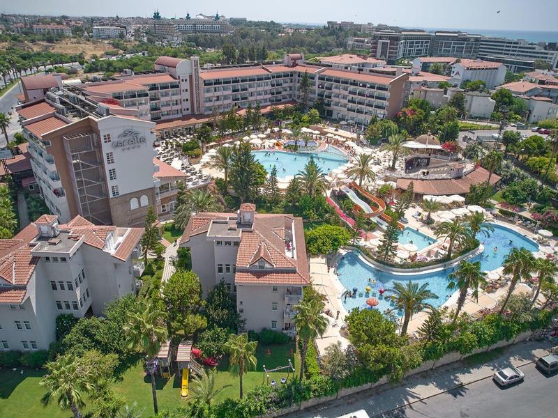 Grand complexe hôtelier avec plusieurs bâtiments et plusieurs grandes piscines entourées de jardins verts.