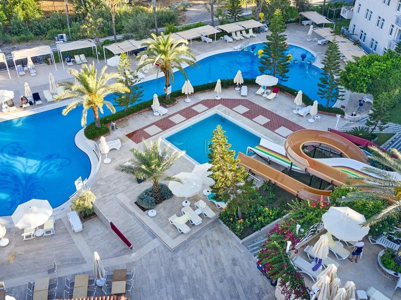 Vue d'une piscine extérieure luxueuse avec chaises longues et palmiers dans un hôtel.