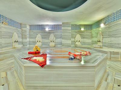 Hammam bien éclairé avec murs en marbre et serviettes décoratives.