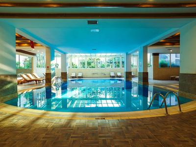 Piscine intérieure d'hôtel avec chaises longues et grandes fenêtres