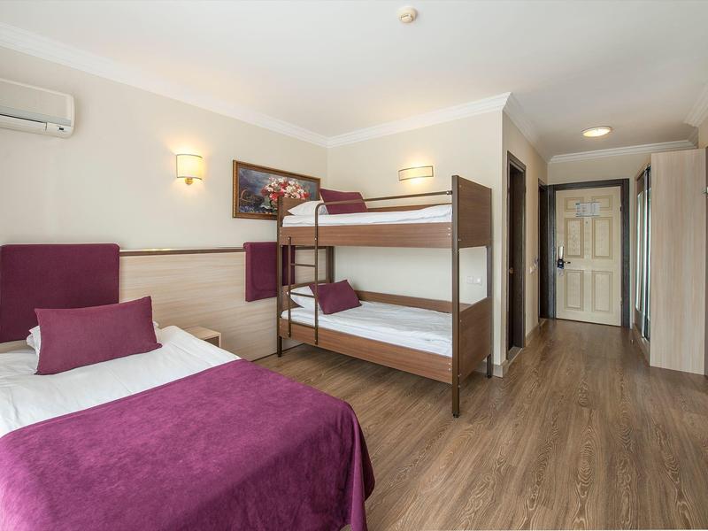 Chambre d'hôtel avec lit simple, lits superposés et sol en bois