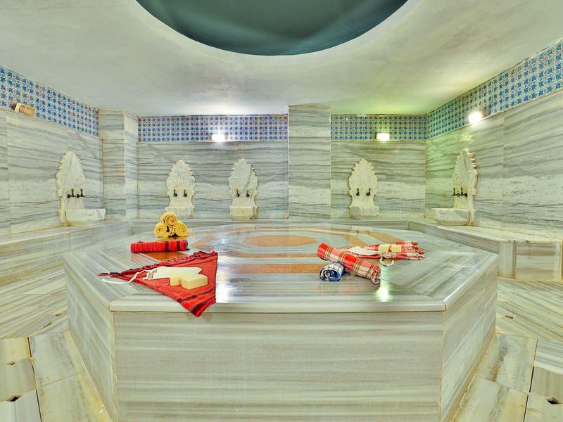 Hammam bien éclairé avec murs en marbre et serviettes décoratives.