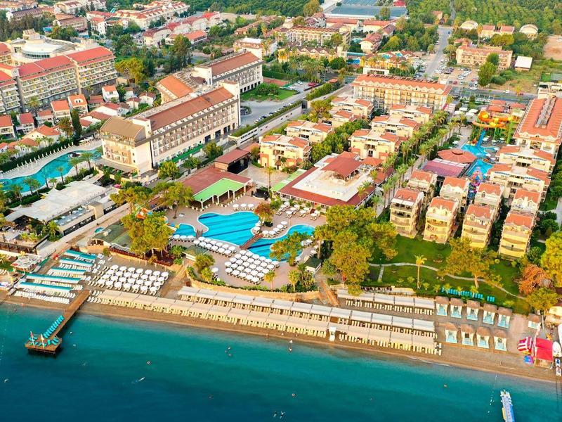 Vue aérienne d'une grande station balnéaire avec piscines, transats et accès direct à la mer.