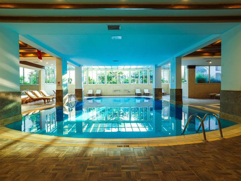 Piscine intérieure d'hôtel avec chaises longues et grandes fenêtres