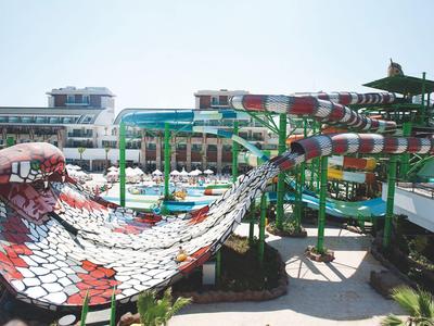 Water park with large colorful water slides next to a hotel building in sunny weather.