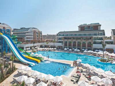 Large outdoor pool with water slides at a hotel resort on a sunny day.