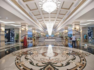 Prostorná hotelová lobby s mramorovou podlahou, zdobenými sloupy a lustry