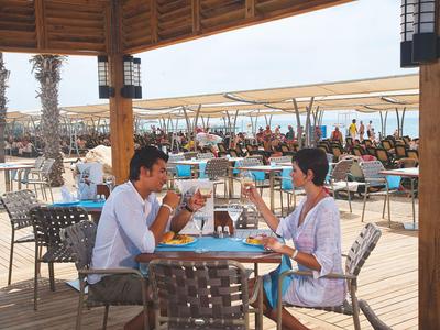 Couple sitting at a table on the open terrace of a beachside restaurant.
