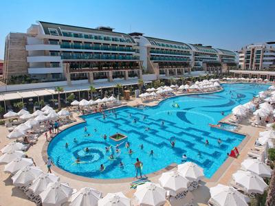 Velký hotelový bazén s deštníky a lehátky pod modrou oblohou.