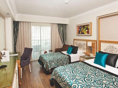 Hotel room with two double beds, decorative pillows, and balcony with outdoor view.