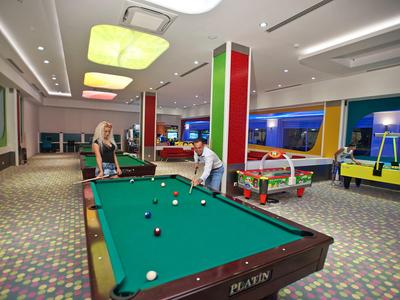 Game room with pool table, air hockey, and foosball, two people playing pool.