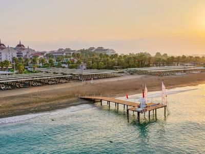 Sunset over a beach with a pier and a hotel in the background.