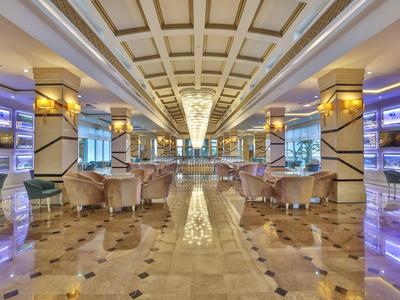 Prostorná luxusní hotelová lobby s lesklou mramorovou podlahou, čalouněnými křesly a osvětlenými stěnami.