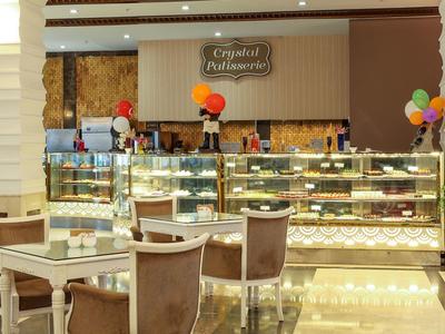 Moderní kavárenská část s prosklenými vitrínami plnými dortů a sezení.