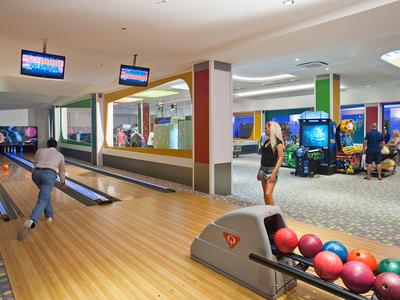 Interior view of a bowling alley with several lanes and guests playing.