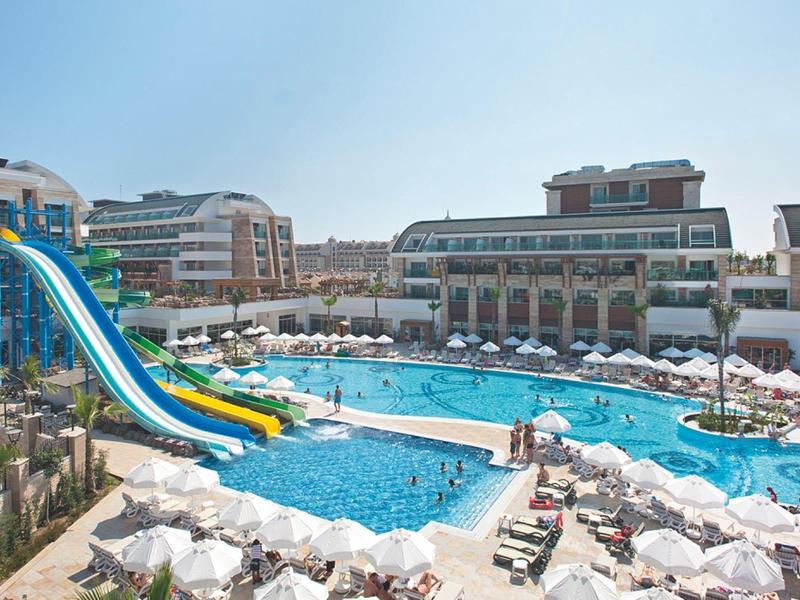 Velká bazénová plocha s vodními skluzavkami a lehátky před rezortním hotelem.
