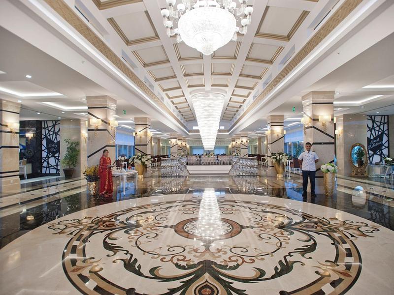 Prostorná hotelová lobby s mramorovou podlahou, zdobenými sloupy a lustry