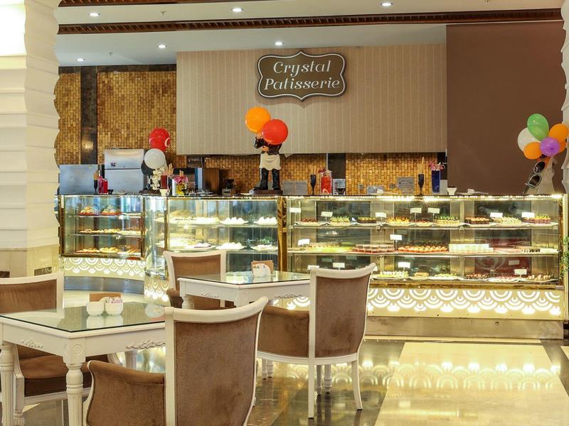 Moderní kavárenská část s prosklenými vitrínami plnými dortů a sezení.