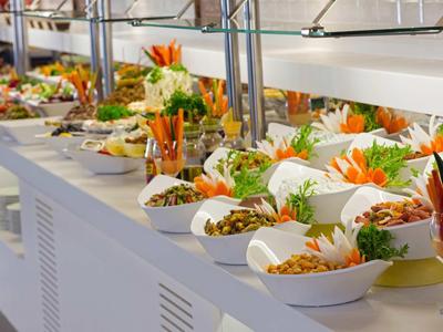 Buffet con vari insalate, verdure e noci disposte in ciotole bianche.