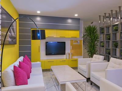 Soggiorno moderno con pareti gialle, mobili bianchi e cuscini rosa.