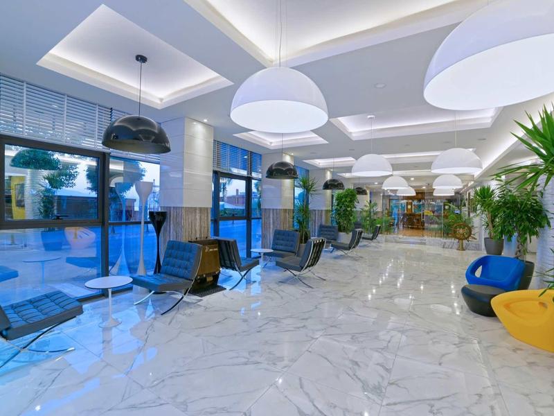 Moderna hall dell'hotel con sedute eleganti, grandi lampade e finestre di vetro.