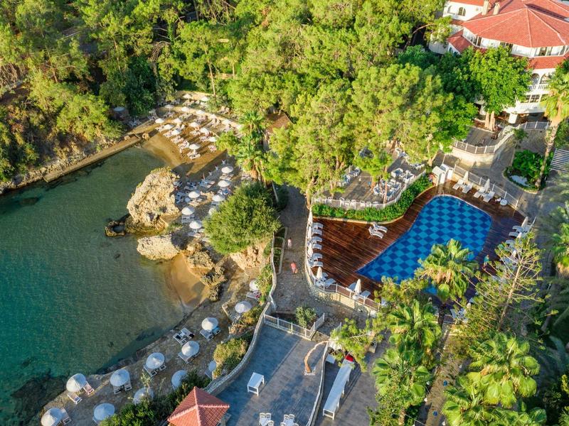 Luftaufnahme eines tropischen Resorts mit Pool, umgeben von grünem Wald und einem kleinen See.