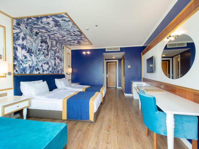 Modernes Hotelzimmer mit zwei Betten, blauen und weißen Farbtönen, Holzfußboden und großem Spiegel.