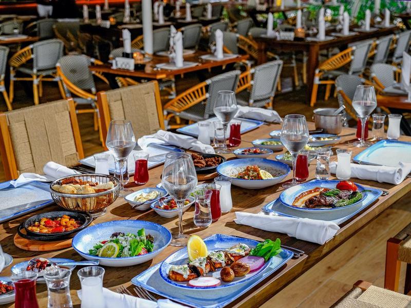 Tisch mit gedeckten Tellern, Gläsern und bunten Speisen in hellem Restaurantambiente.