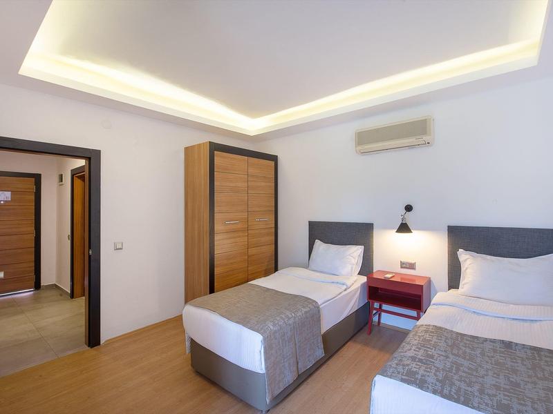 Schlichtes Doppelzimmer mit zwei Einzelbetten, Holzboden, Kleiderschrank und Klimaanlage an der Wand.