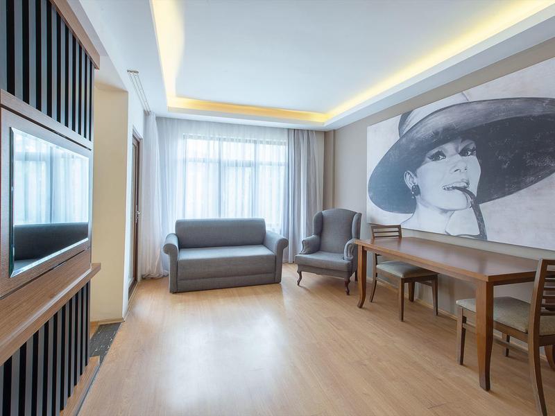 Modern eingerichteter Raum mit Sofa, Sesseln, großem Wandbild und floralen Teppichen.