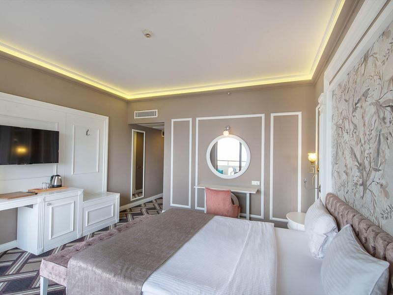 Modernes Schlafzimmer mit großen Betten, Teppichboden, Rundspiegel und sanfter Wandbeleuchtung.