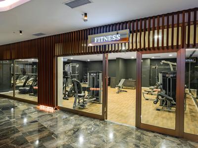 Vista della palestra di un hotel con varie attrezzature da allenamento dietro pareti di vetro.