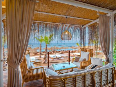 Gemütliche Strandlounge aus Holz mit hellem Korbmöbel und Blick auf Meer und Himmel.