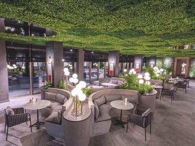 Moderner Außenbereich mit runden Sofas, Stühlen, Tischen und Blumendekorationen bei Dämmerung.