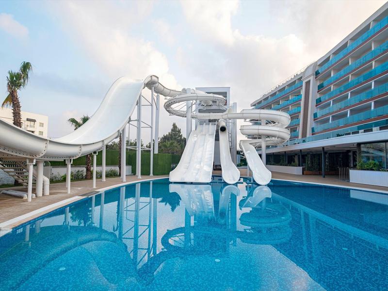 Ein modernes Schwimmbad mit mehreren weißen Wasserrutschen und klarem blauem Wasser.