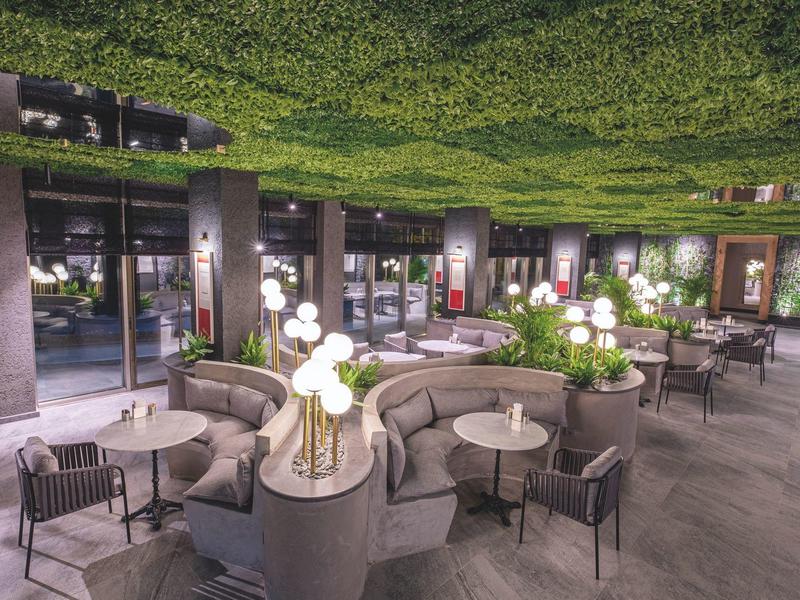 Moderner Außenbereich mit runden Sofas, Stühlen, Tischen und Blumendekorationen bei Dämmerung.