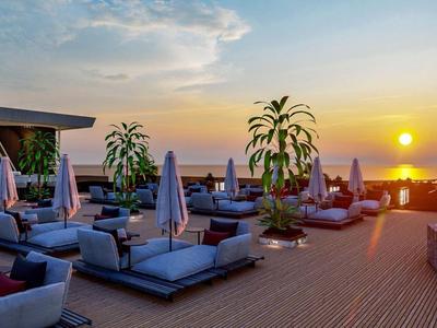 Terrazza sul tetto con posti a sedere moderni e vista sul tramonto sull'acqua.