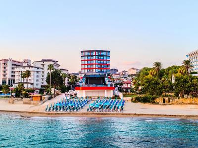 Spiaggia con sedie a sdraio blu davanti a un hotel moderno sull'acqua al tramonto