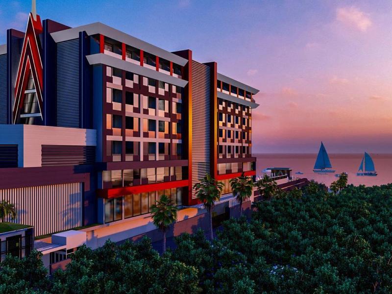 Immeuble d'hôtel moderne avec accents colorés au bord de la mer au coucher du soleil et voiliers sur l'eau.