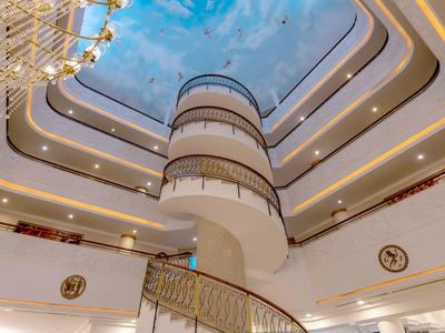 Kręcone schody w jasnym holu hotelowym z nowoczesnym oświetleniem sufitowym i ozdobną balustradą.