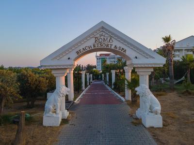 Eingang mit weißen Löwenstatuen zu einem Beach Resort Park bei klarem Himmel