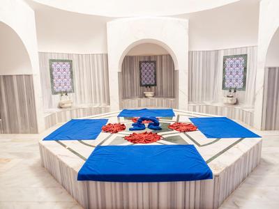 Innenansicht eines türkischen Hamams mit zentralem Marmorbecken und blauen Handtüchern