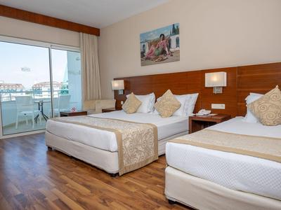 Modernes Hotelzimmer mit zwei Betten, Holzfußboden und Balkon mit Stadtblick.