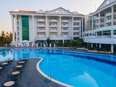 Hotel mit großem, geschwungenem Außenpool und weißen Balkonen.