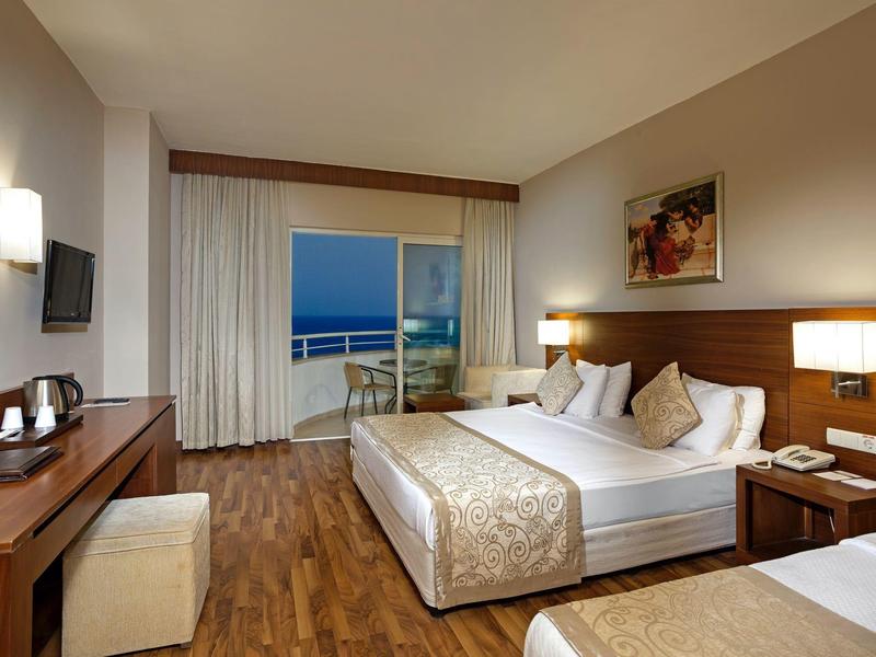 Camera d'hotel moderna con letto matrimoniale, balcone e vista mare.