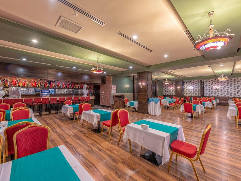 Ampia sala banchetti elegante con tavoli decorati e sedie rosse.