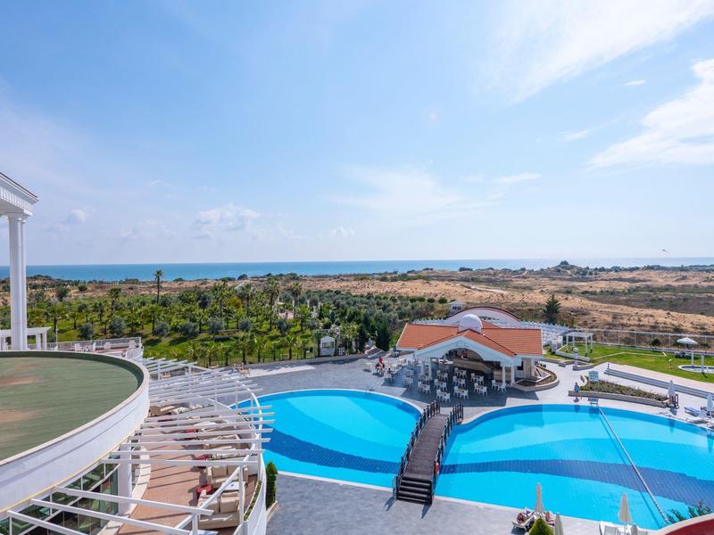 Vista su una piscina dell'hotel con ponte e mare sullo sfondo con cielo sereno.