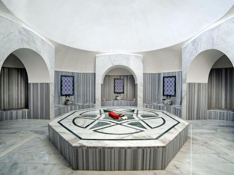 Interno di un bagno turco tradizionale con vasca in marmo e soffitti a volta.