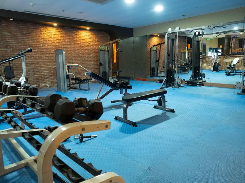 Palestra luminosa con varie attrezzature per l'allenamento e tappetini blu.